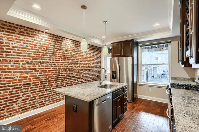a kitchen with stainless steel appliances granite countertop a sink and wooden floor