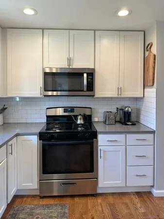 a kitchen with stainless steel appliances granite countertop a stove a microwave and a white cabinets