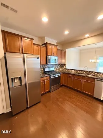 a kitchen with stainless steel appliances granite countertop a refrigerator a stove a sink and a microwave