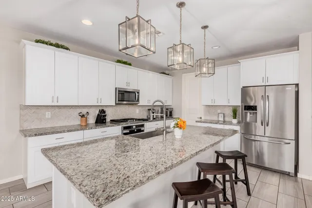 a open kitchen with stainless steel appliances granite countertop a stove a sink dishwasher a microwave oven with white cabinets and couches