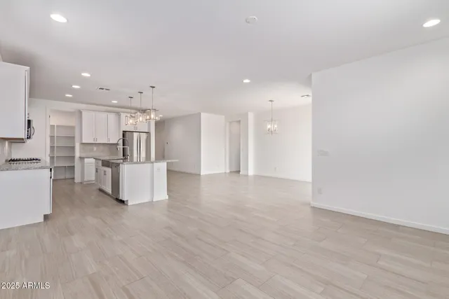 a kitchen with stainless steel appliances granite countertop a refrigerator a sink dishwasher a stove and white cabinets with wooden floor