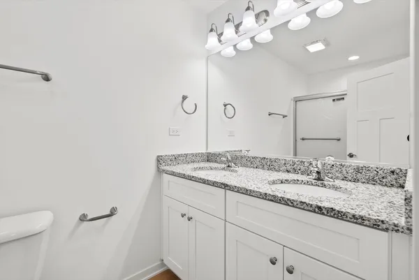 a bathroom with a granite countertop sink a toilet and a mirror