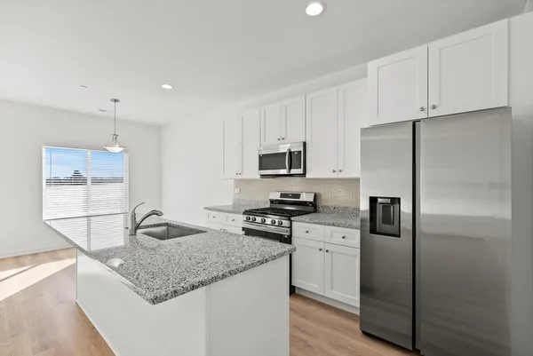 a kitchen with stainless steel appliances granite countertop a sink stove and refrigerator