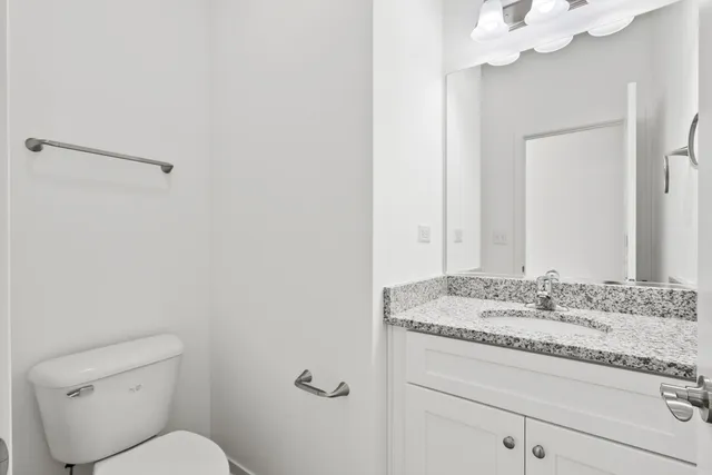 a bathroom with a granite countertop sink mirror vanity and toilet