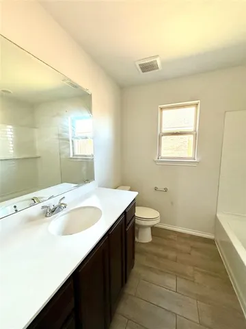 a bathroom with a granite countertop sink a toilet and a mirror