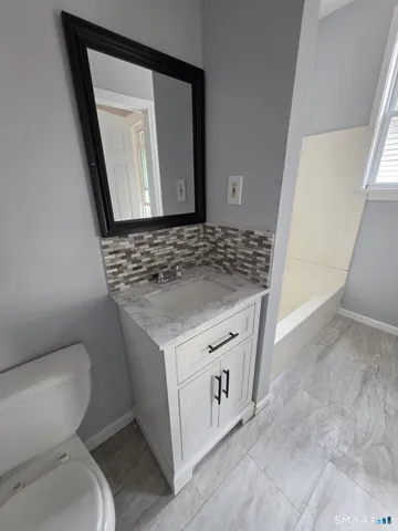 a bathroom with a granite countertop toilet sink and mirror