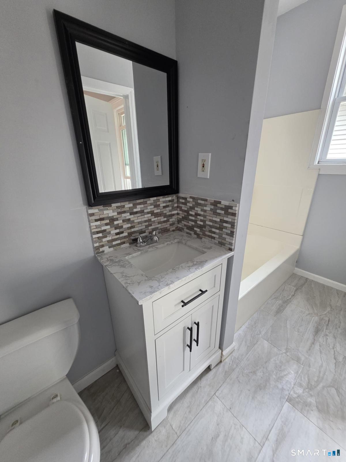 282 Pequonnock Street, Unit 2 Bridgeport, CT 06604 - Photo 6 of 7 a bathroom with a granite countertop toilet sink and mirror