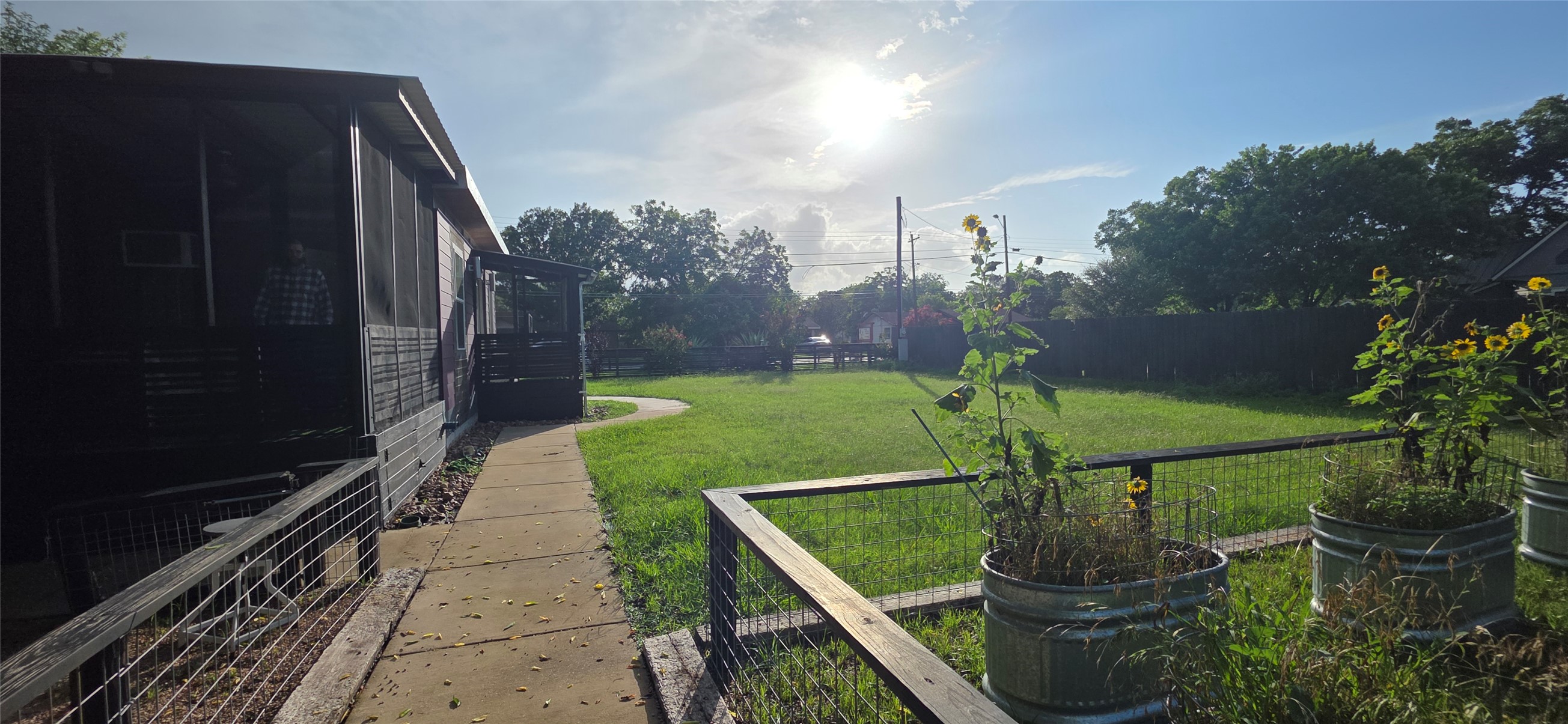 916 South Main Street Lockhart, TX 78644 - Photo 13 of 18 A well-maintained lawn stretches out to a privacy fence, framed by garden planters and a charming screened-in porch.