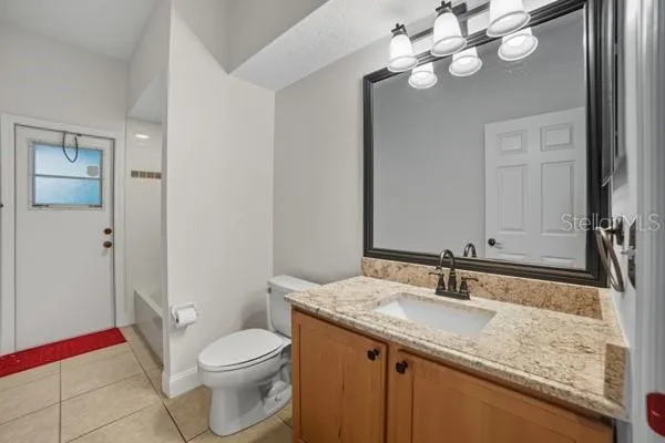 a bathroom with a granite countertop sink a toilet and a mirror