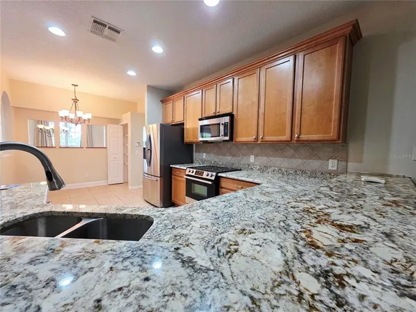 a kitchen with stainless steel appliances kitchen island granite countertop a stove a sink and a microwave
