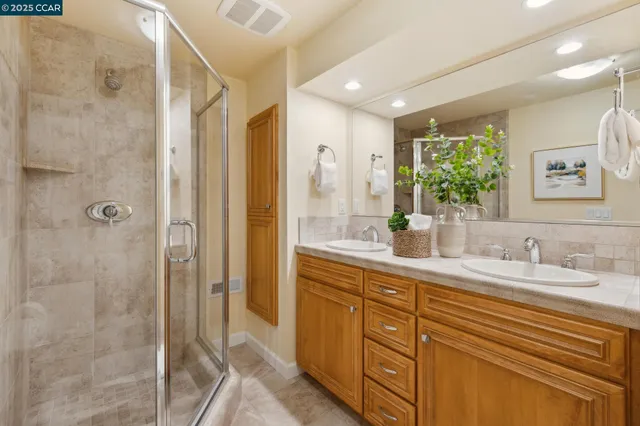 a bathroom with a double vanity sink mirror and shower