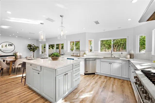a kitchen with sink a stove and white cabinets with wooden floor