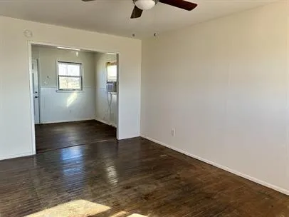 an empty room with wooden floor cabinet and windows