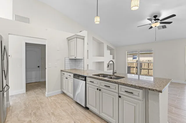 a kitchen with stainless steel appliances granite countertop a sink a stove and cabinets
