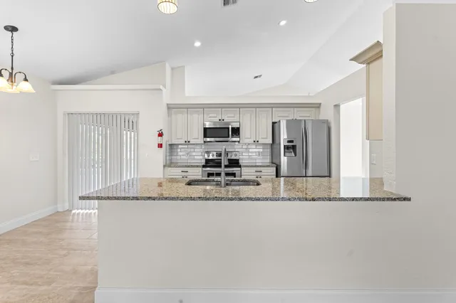 a large kitchen with granite countertop a sink and stainless steel appliances