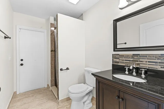 a bathroom with a granite countertop sink toilet and mirror