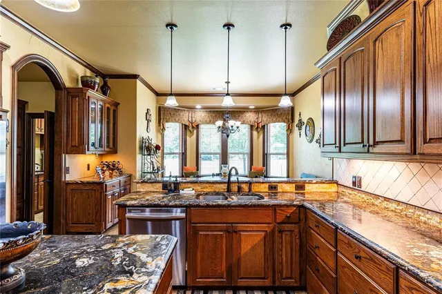 a kitchen with stainless steel appliances granite countertop a sink a stove and a wooden floors