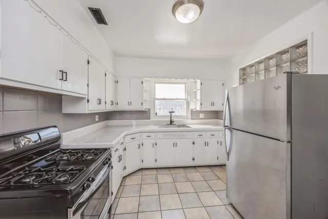a kitchen with granite countertop a refrigerator stove and white cabinets