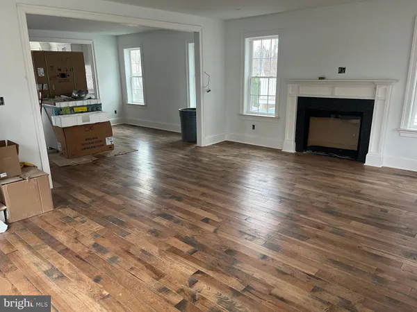 an empty room with wooden floor a fireplace and windows