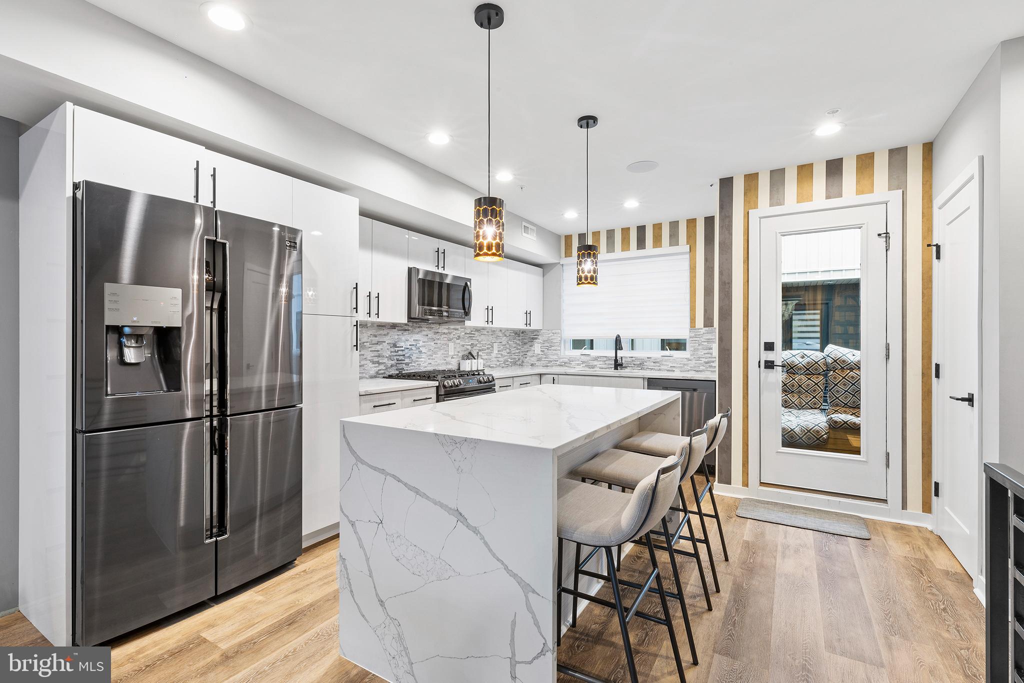 815 Perkiomen Street, Unit 15 Philadelphia, PA 19130 - Photo 5 of 27 a kitchen with stainless steel appliances kitchen island granite countertop a refrigerator a oven a sink with a dining table and chairs
