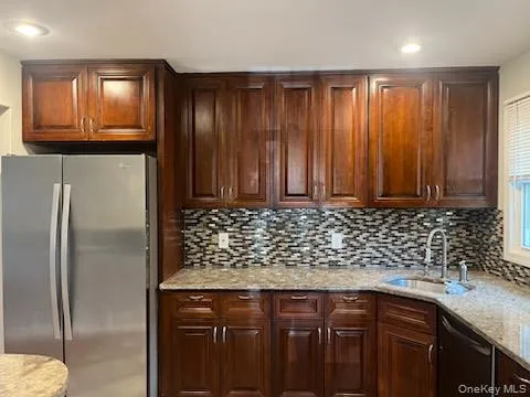 a kitchen with stainless steel appliances granite countertop a refrigerator a sink dishwasher and wooden cabinets with wooden floor