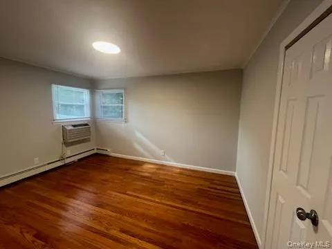 a view of an empty room with window and wooden floor