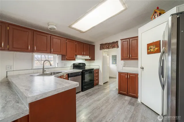 a kitchen with stainless steel appliances granite countertop a refrigerator a sink dishwasher a stove with wooden cabinets and floor