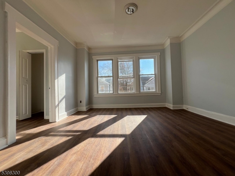 55 Schley Street Newark, NJ 07112 - Photo 3 of 8 an empty room with wooden floor and windows