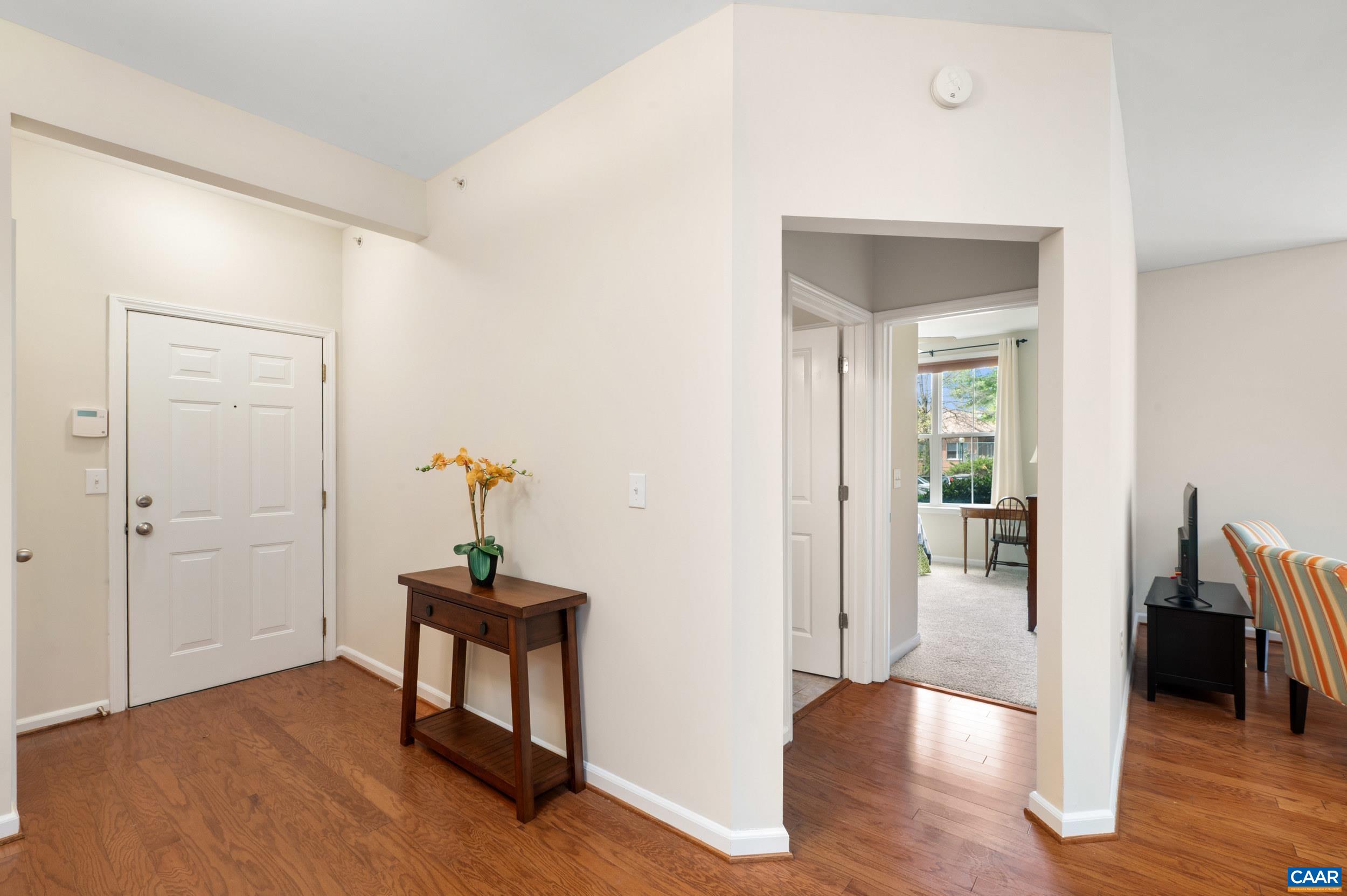 765 Walker Square, Unit 2D Charlottesville, VA 22903 - Photo 16 of 33 a view of a hallway to a livingroom with wooden floor and furniture