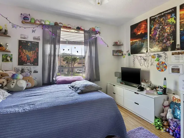 a bedroom with a bed flat screen tv and a large window