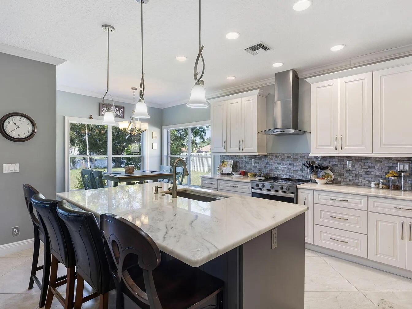 7782 Hoffy Circle Lake Worth, FL 33467 - Photo 8 of 27 a kitchen with stainless steel appliances kitchen island granite countertop a table chairs in it and white cabinets
