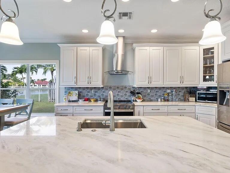 7782 Hoffy Circle Lake Worth, FL 33467 - Photo 10 of 27 a kitchen with stainless steel appliances kitchen island granite countertop a stove a sink and a white cabinets