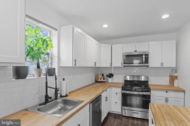 a kitchen with stainless steel appliances granite countertop a sink a stove a microwave a sink a refrigerator and a stove