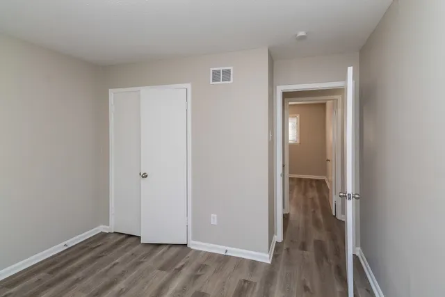 an empty room with wooden floor & closet area