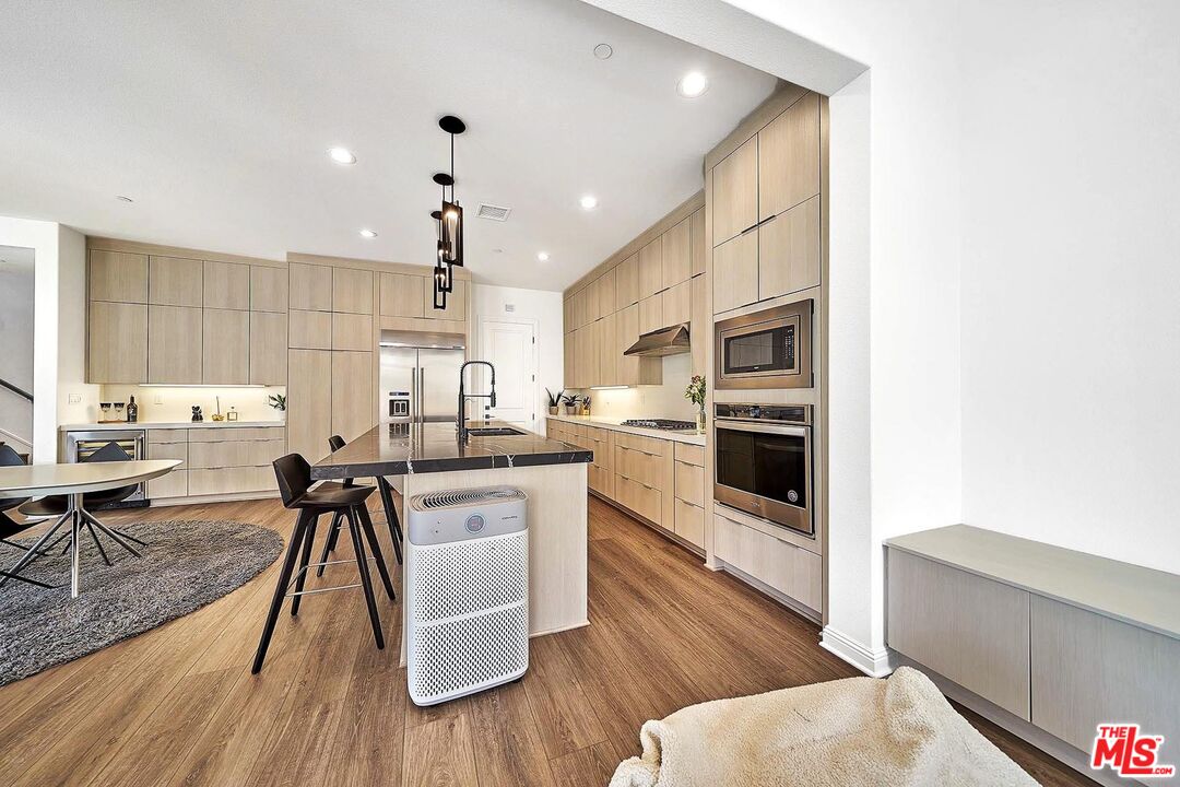 20641 Walnut Circle Porter Ranch, CA 91326 - Photo 15 of 47 a kitchen with stainless steel appliances kitchen island granite countertop a stove top oven a sink a dining table and chairs with wooden floor