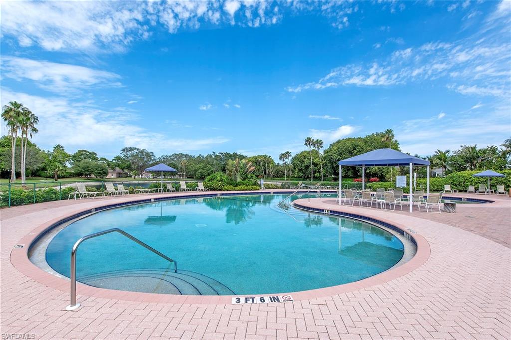 7001 Lone Oak Boulevard Naples, FL 34109 - Photo 25 of 25 a view of a swimming pool with a table and chairs under an umbrella