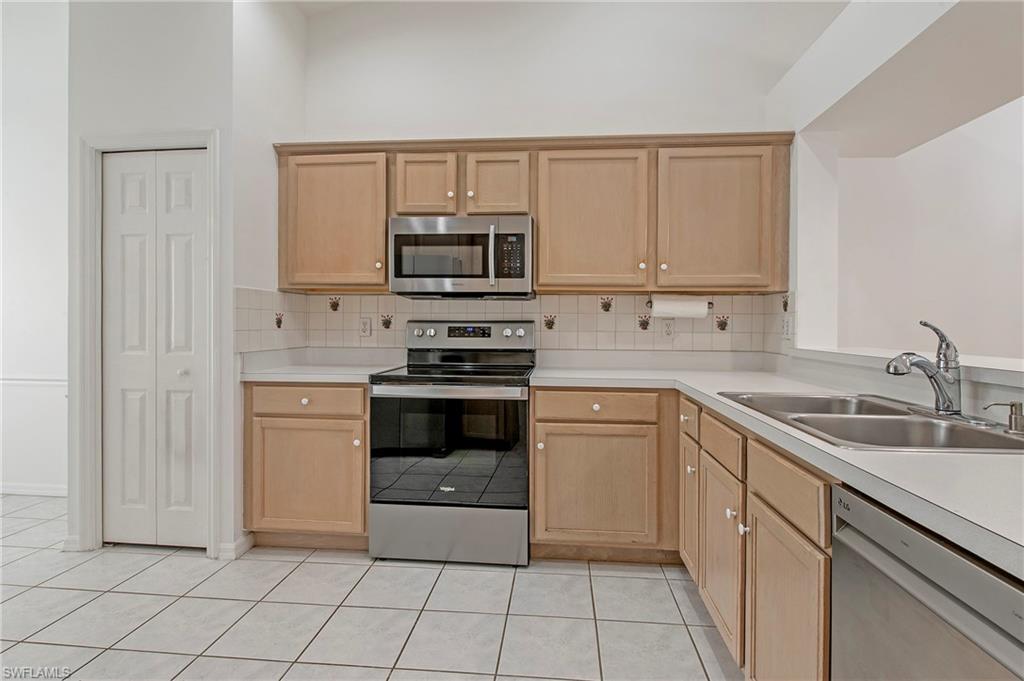 7001 Lone Oak Boulevard Naples, FL 34109 - Photo 8 of 25 a kitchen with white cabinets stainless steel appliances and a sink