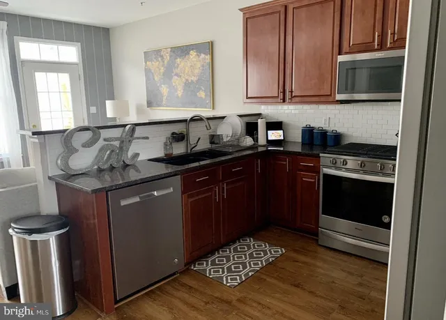 a kitchen with stainless steel appliances granite countertop a stove a sink and a microwave