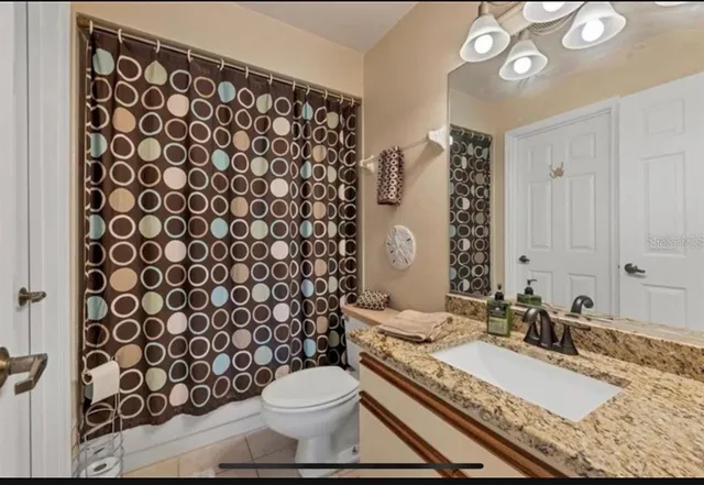 a bathroom with a granite countertop toilet a sink and a mirror
