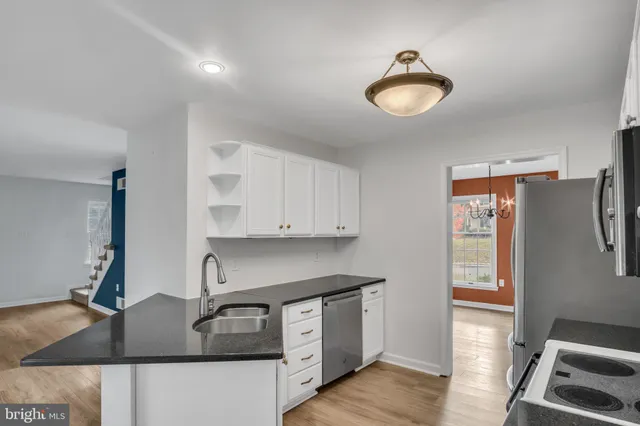 a kitchen with stainless steel appliances a sink a stove top oven a refrigerator cabinets and a dining table