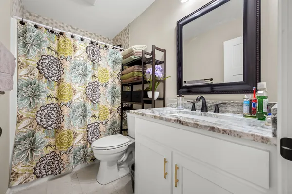 a bathroom with a granite countertop sink mirror vanity and toilet