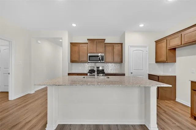 a kitchen with stainless steel appliances granite countertop a sink a stove a microwave a sink a refrigerator and cabinets