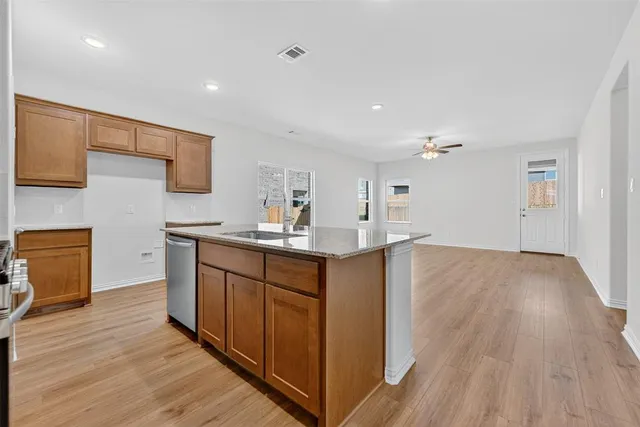 a kitchen with kitchen island granite countertop wooden floors and wide window