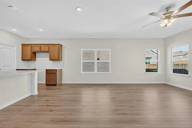 a view of an empty room with window and wooden floor