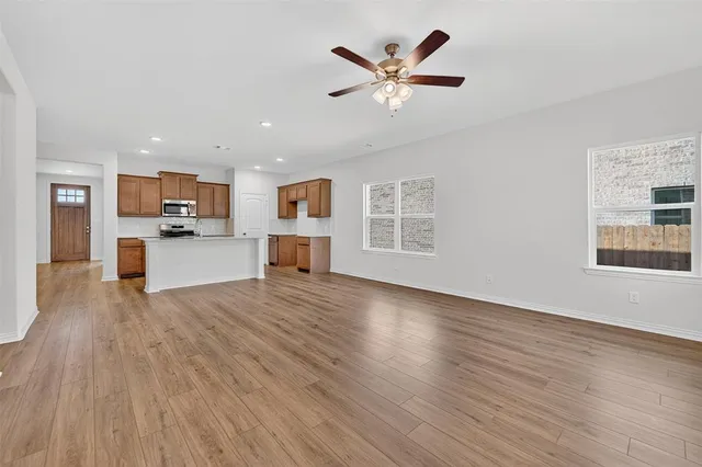 a view of a kitchen with furniture a ceiling fan and wooden floor