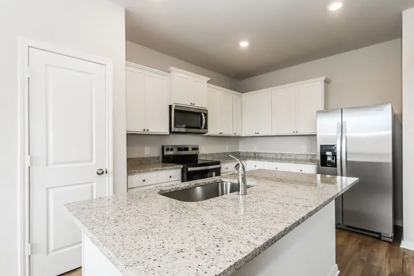 a kitchen with granite countertop a sink a counter top space cabinets stainless steel appliances and a counter space