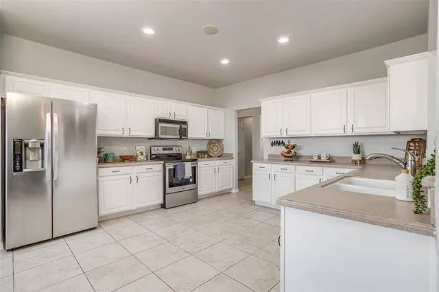 a large white kitchen with cabinets a sink and appliances