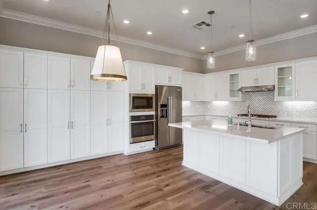 a kitchen with stainless steel appliances granite countertop a sink a stove and a refrigerator