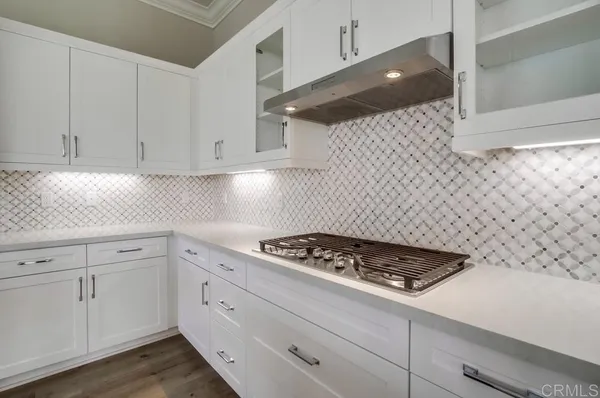 a kitchen with white cabinets and stove
