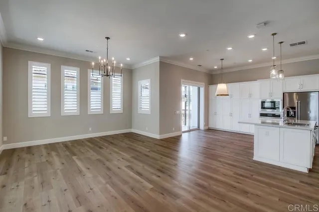 a view of an empty room with kitchen and window